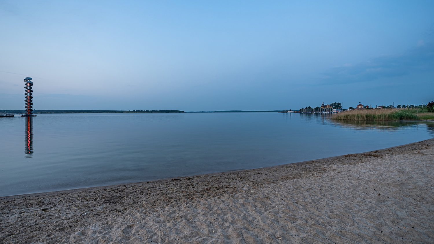 Der Goitzschesee bei Bitterfeld mit dem Pegelturm im Wasser, im Vordergrund der Sandstrand